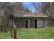 Rustic outbuilding with wooden siding and sliding door, surrounded by overgrown grass at 4480 S Franklin St, Cherry Hills Village, CO 80113