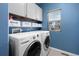 Efficient laundry room with modern washer and dryer, overhead cabinets, and a window for natural light at 3917 Starry Night Loop, Castle Rock, CO 80109