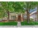 Charming home featuring a brick facade, covered porch, and beautifully landscaped front yard with mature trees at 6900 W Grant Ranch Blvd # 59, Littleton, CO 80123