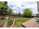 Backyard shows a manicured lawn, garden beds, and a wood deck near a perimeter fence and mature trees at 7072 Palisade Dr, Highlands Ranch, CO 80130