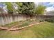 Manicured backyard shows brick garden beds surrounding a lawn, and a tall wood fence as a backdrop at 7072 Palisade Dr, Highlands Ranch, CO 80130
