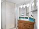 This bathroom features a frosted glass shower, teal tile counters, and a wood vanity with ample lighting at 7072 Palisade Dr, Highlands Ranch, CO 80130