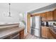Modern kitchen design showcasing stainless steel refrigerator, wooden cabinets, and an adjacent staircase at 7072 Palisade Dr, Highlands Ranch, CO 80130