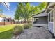 Backyard featuring flagstone patio and enclosed sunroom, surrounded by trees and greenery at 14625 Vine St, Thornton, CO 80602
