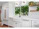 Bright kitchen with a farmhouse sink, white cabinets, and a large window overlooking the backyard at 3380 S Ogden St, Englewood, CO 80113