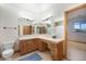 Spacious bathroom featuring a long vanity with double mirrors, a sink, and wooden cabinets at 497 Grey Squirrel Way, Franktown, CO 80116