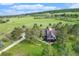 Aerial view of a well-maintained home with mature trees, a long driveway, and surrounded by green fields and forests at 497 Grey Squirrel Way, Franktown, CO 80116