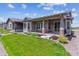 An inviting backyard featuring a covered patio with stone pillars and a lush green lawn at 22656 E Glidden Dr, Aurora, CO 80016