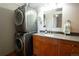 Bathroom featuring a single vanity, granite countertop, wood cabinets, and stacked washer and dryer at 2261 Blake St # 5H, Denver, CO 80205
