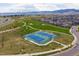 Aerial view of the blue tennis courts in a green community surrounded by lush landscapes and mountain views at 18926 W 94Th Ave, Arvada, CO 80007