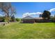 Home exterior showcasing a brick accent wall, large grassy yard and mature trees at 90 Ammons St, Lakewood, CO 80226