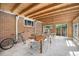 Covered brick patio with exposed beams, a dining table, and a view of the yard at 90 Ammons St, Lakewood, CO 80226