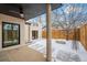 Covered back patio with snow-covered stone pavers, pillars, and view of the backyard and fence at 2434 Mapleton Ave, Boulder, CO 80304