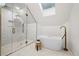 Modern bathroom featuring white tiles, a glass-enclosed shower, gold fixtures, and soaking tub at 2434 Mapleton Ave, Boulder, CO 80304