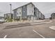 Modern condo building featuring gray siding, white trim, and individual garages, set against a cloudy sky at 16841 Askins Loop # 105, Parker, CO 80134