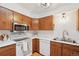 Bright kitchen featuring wood cabinets, stainless steel microwave, white appliances, and a modern faucet at 2393 E 90Th Ave, Thornton, CO 80229