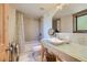 Bright bathroom features a vanity with glass countertop and vessel sink and a tub with beige tile surround at 4545 King St, Denver, CO 80211