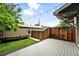 Fenced backyard features a deck area and a small patch of grass with planter boxes and string lights at 2077 S Clayton St, Denver, CO 80210