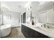 Bright bathroom featuring dual sinks, modern vanity, and a soaking tub at 2077 S Clayton St, Denver, CO 80210
