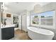 Bright bathroom featuring dual sinks, modern vanity, and a soaking tub at 2077 S Clayton St, Denver, CO 80210