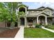 Charming two-story home with stone accents, a covered porch, landscaped yard, and a mature tree in front at 2077 S Clayton St, Denver, CO 80210