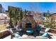 Charming backyard with stone fireplace, outdoor seating, and lush greenery for relaxation and entertainment at 15798 Weaver Gulch Dr, Morrison, CO 80465