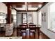 Bright dining room with wood-trimmed ceiling beams, dark-stained wood floors, stone accent wall, and backyard views at 15798 Weaver Gulch Dr, Morrison, CO 80465