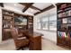 Charming home office featuring custom wood built-in bookshelves, a coffered ceiling, and a large window at 15798 Weaver Gulch Dr, Morrison, CO 80465