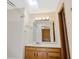 Bright bathroom with a skylight, wood vanity, and white tiled shower and floors at 1816 S Pagosa Way # 5, Aurora, CO 80017