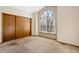Bedroom with a large window and neutral carpet and paint, featuring a closet with sliding wooden doors at 1816 S Pagosa Way # 5, Aurora, CO 80017