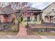 Charming home featuring a covered front porch and decorative wrought iron fence with colorful trees and landscaping at 3313 Curtis St, Denver, CO 80205