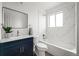 Bathroom with blue vanity, sleek sink, and shower-tub combination with tiled walls at 13438 E 13Th Pl, Aurora, CO 80011