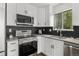Updated kitchen featuring stainless steel appliances, sleek white cabinets, and dark backsplash at 13438 E 13Th Pl, Aurora, CO 80011
