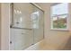 Bathroom featuring a shower over tub, grab bar, glass shower door, and a bright window for natural light at 3575 W Hamilton Pl, Denver, CO 80236
