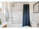 Well-lit bathroom featuring tub with shower, blue curtain, subway tiles, and neutral wall art at 4131 Quivas St, Denver, CO 80211