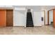 Spacious finished basement featuring tile flooring, staircase, and multiple doorways at 1591 S Zuni St, Denver, CO 80223