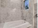 Luxurious bathroom featuring a soaking tub with gray marble-look tile surround at 10197 E Mississippi Ave, Aurora, CO 80247