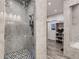 Modern bathroom with a glass-enclosed shower, gray tile walls, black and white tiled floor, and open closet at 10197 E Mississippi Ave, Aurora, CO 80247