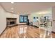 Open-concept living room with hardwood floors, brick fireplace and view into adjacent kitchen at 8075 S Harrison Way, Centennial, CO 80122