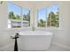 Modern bathroom with white freestanding bathtub, large windows, and a peaceful view at 280 Ammons St, Lakewood, CO 80226
