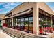 Restaurant patio with red tables and chairs beneath awnings, enclosed by a wooden fence and brick exterior at 655 Stonebridge Dr, Longmont, CO 80503