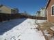 Wide backyard with a wood fence and a thin layer of snow covering sparse lawn and nearby houses at 25858 E Bayaud Ave, Aurora, CO 80018