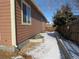 Side yard of brown home featuring partially snow-covered lawn, wood fence, and a few trees at 25858 E Bayaud Ave, Aurora, CO 80018