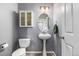 Cozy powder room with a white pedestal sink, gray walls, a matching toilet, and a white medicine cabinet at 291 Las Lomas St, Brighton, CO 80601