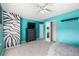 Bright bedroom features unique zebra accent wall, a dresser with TV, blue-green walls, and neutral carpet at 291 Las Lomas St, Brighton, CO 80601