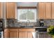 This bright kitchen features wooden cabinets, granite countertops and backsplash, a kitchen window, and stainless appliances at 291 Las Lomas St, Brighton, CO 80601