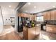 Well-lit kitchen features wood cabinets, stainless appliances, a kitchen island with granite countertops, and tiled flooring at 291 Las Lomas St, Brighton, CO 80601