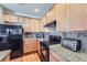 Kitchen featuring wood cabinets, granite countertops, and black appliances at 13001 Grant Cir # C, Thornton, CO 80241