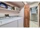 Efficient laundry area with washer, dryer, shelving and storage, conveniently located near the stairs at 7751 S Curtice Dr # E, Littleton, CO 80120