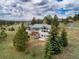 Stunning exterior view of a home with mature trees and a beautifully landscaped yard and distant mountain view at 25803 Aspen Way, Golden, CO 80401